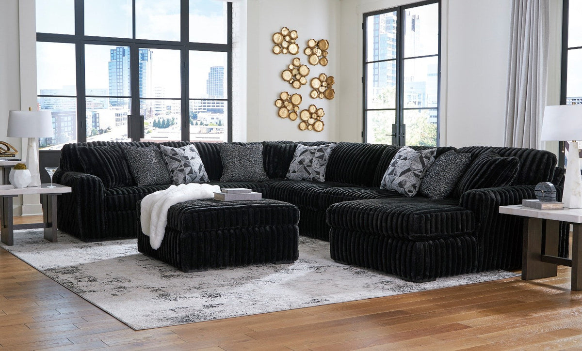 Ashley Midnight-Madness Onyx four-piece sectional in room with separately sold ottoman in foreground
