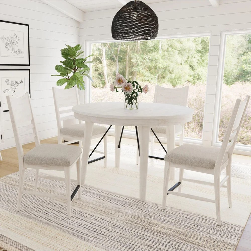 Full view of the Elements International round counter height dining table set in a bright, airy room with windows overlooking nature, showcasing its charming farmhouse style.