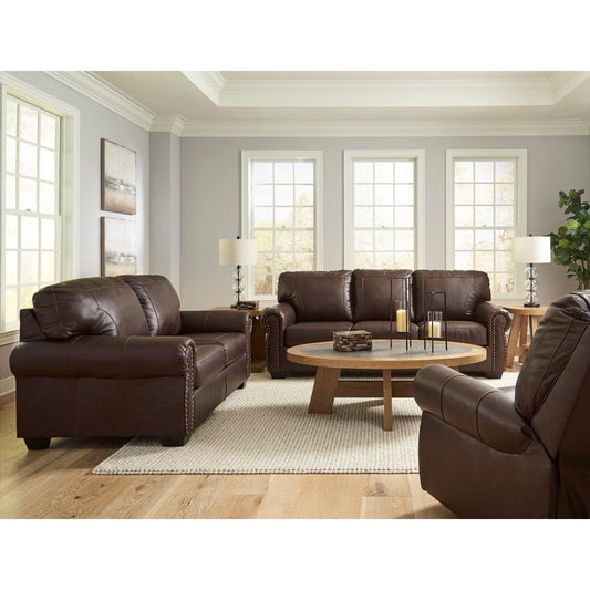 A full living room scene showcasing the dark brown loveseat, sofa, and recliner in a bright, traditionally styled space with light gray walls and large windows.