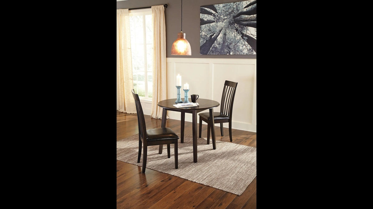 Alternative lifestyle shot showcasing a dark wood round dining table with two matching slatted-back chairs, presented in a cozy, classic setting.