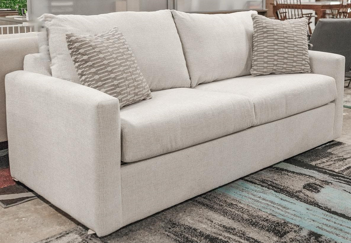 Full front-angle view of the OVER Brax Cera sofa, showcasing its complete design and two accent pillows.