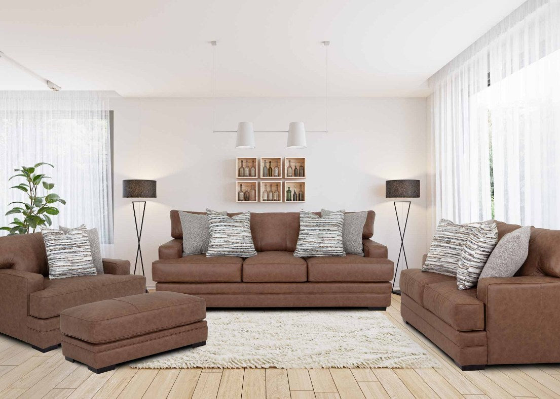 Full living room set (sofa, loveseat, chair, and ottoman) featuring a rich, warm brown leather-look upholstery, plush cushions, wide padded arms, and two striped throw pillows, set in a bright, inviting room.